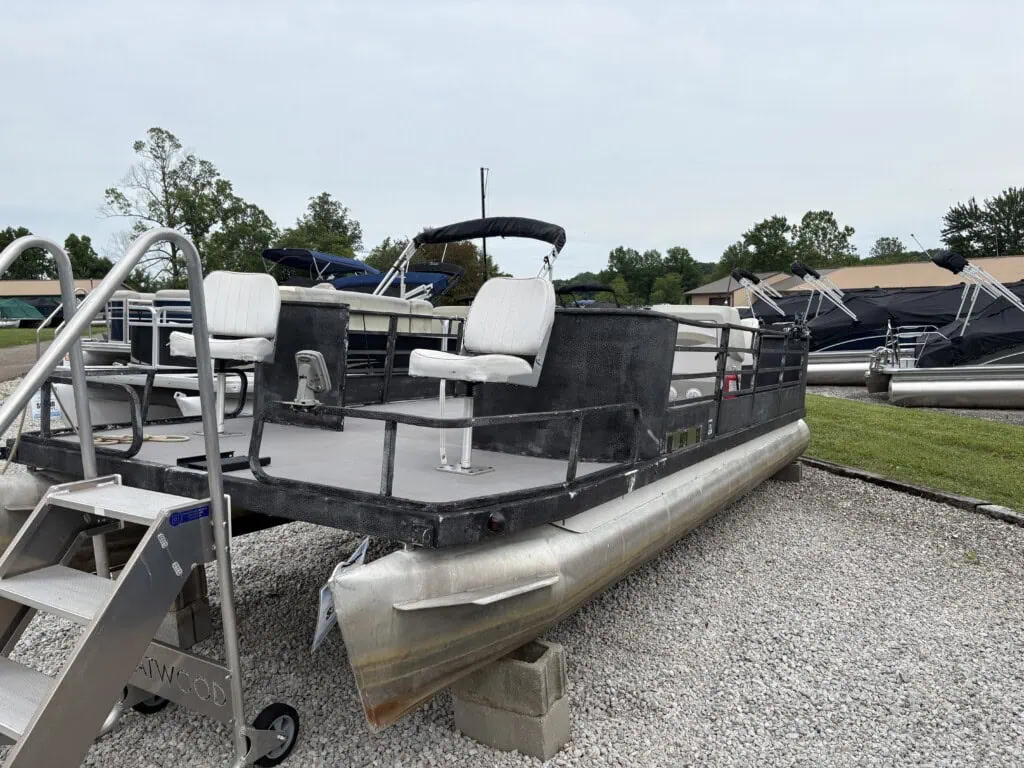 Pontoon boat on blocks in gravel lot