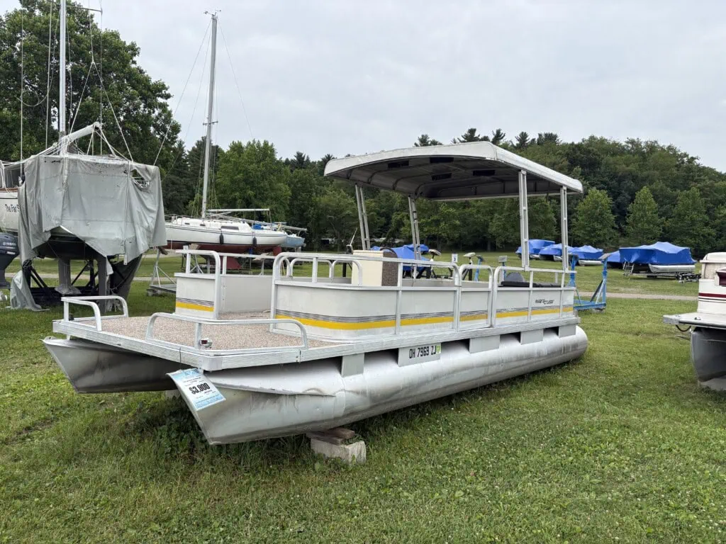 Pontoon boat on display in grassy boatyard