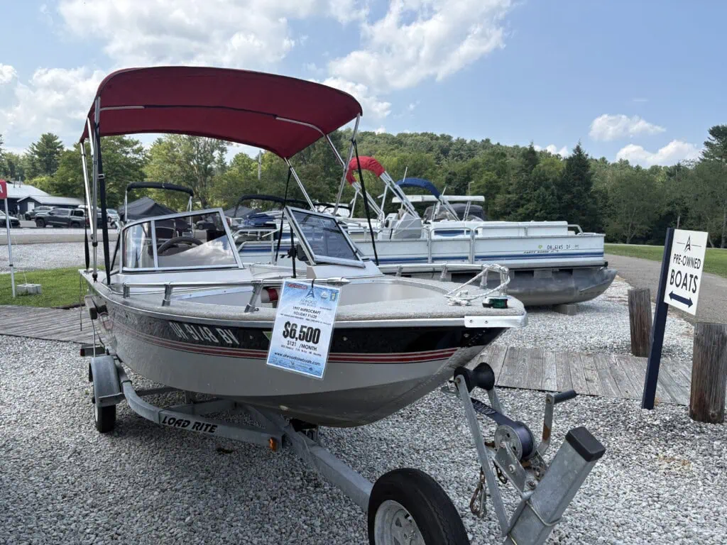 Pre-owned motorboat on trailer with red canopy