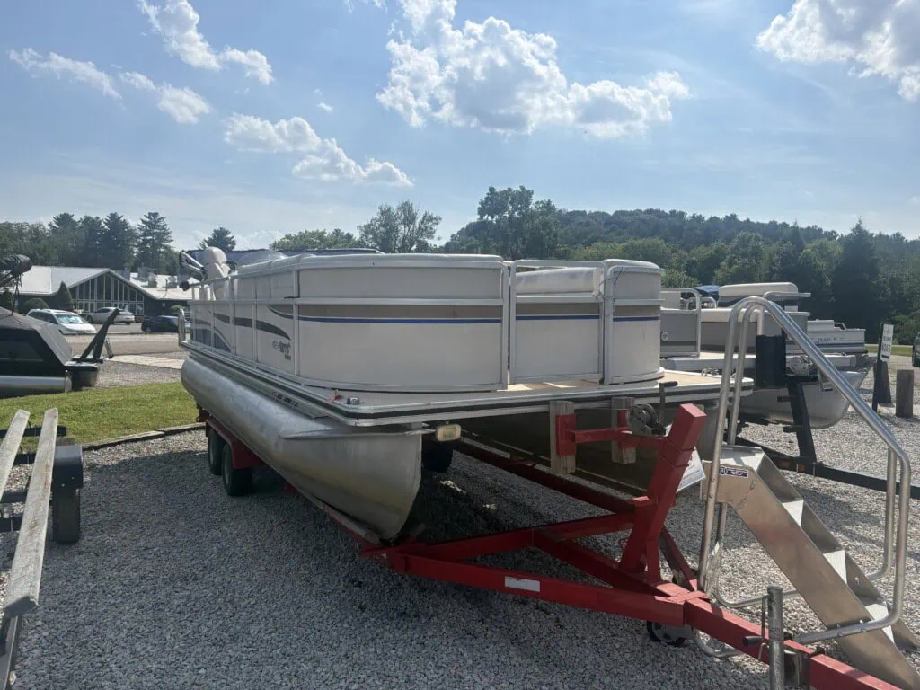 Pontoon boat on trailer in gravel lot