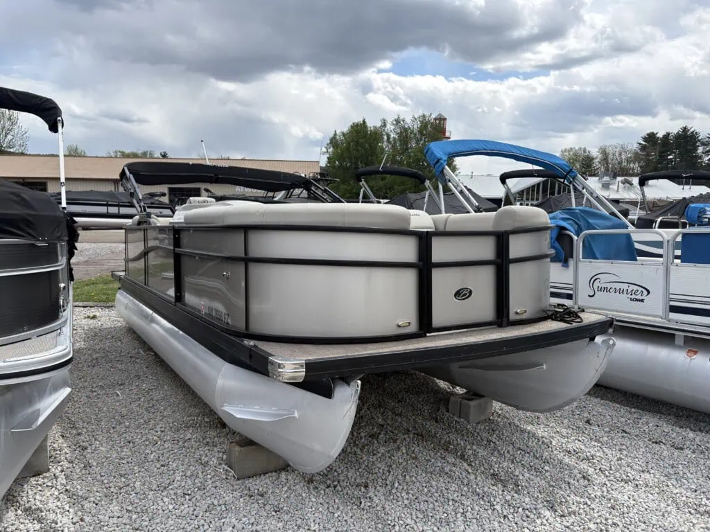 Pontoon boats parked on gravel lot under cloudy sky