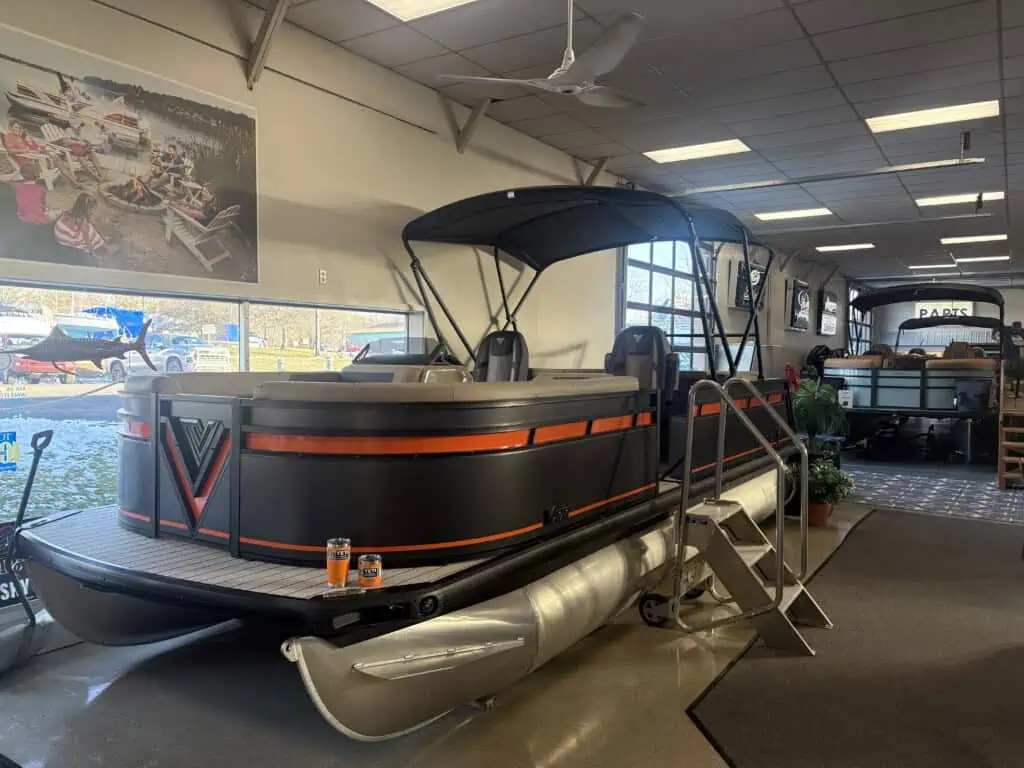 Luxury pontoon boat displayed in showroom interior.