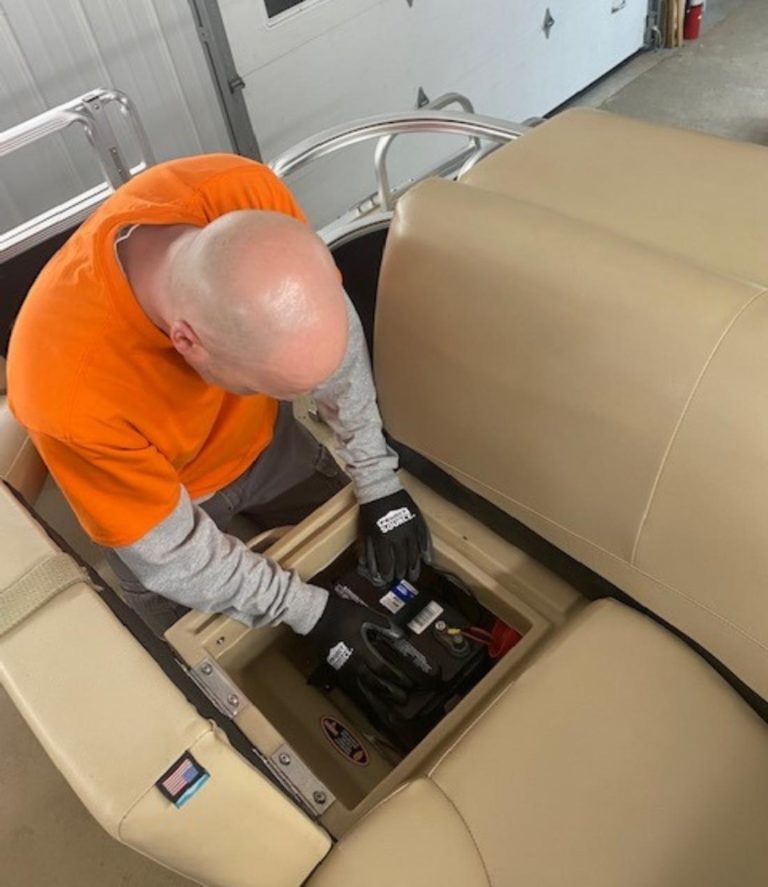 Boat mechanic replacing a battery on a pontoon