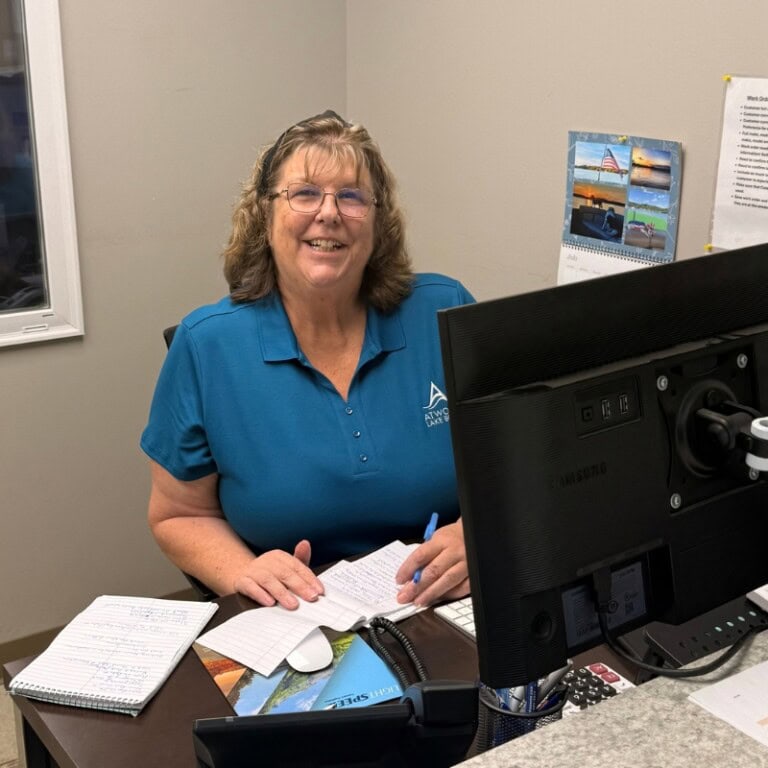 Smiling office employee writing notes at desk