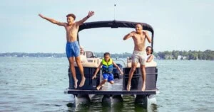 Kids jumping off family pontoon boat into lake.