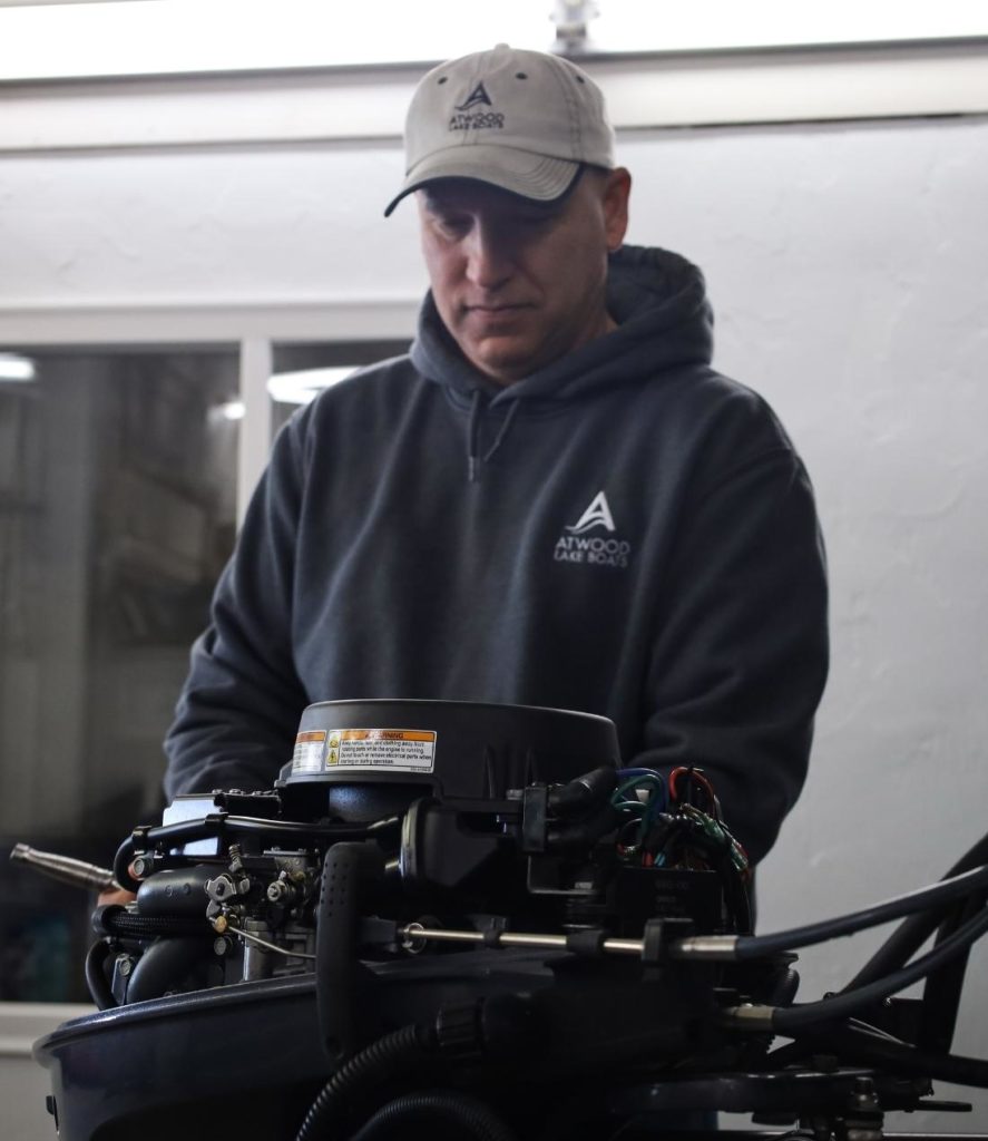 boat mechanic working on outboard engine representing outboard engine winterization