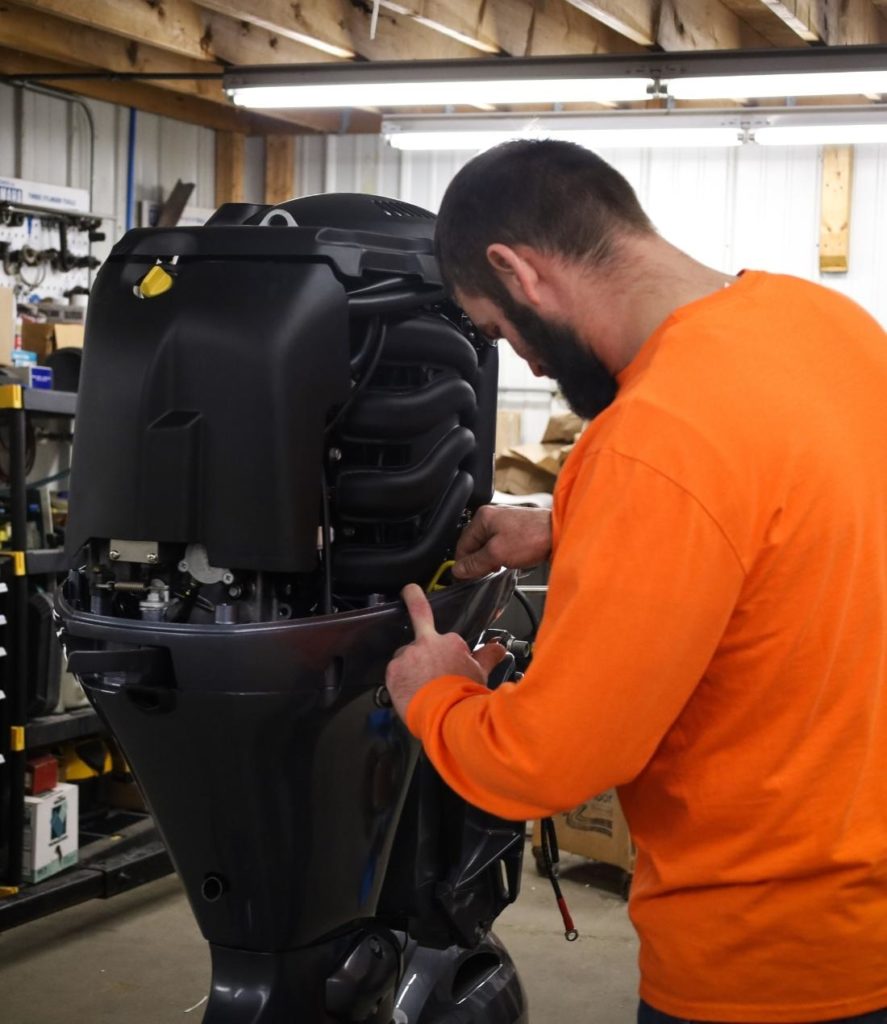 boat mechanic working on outboard motor