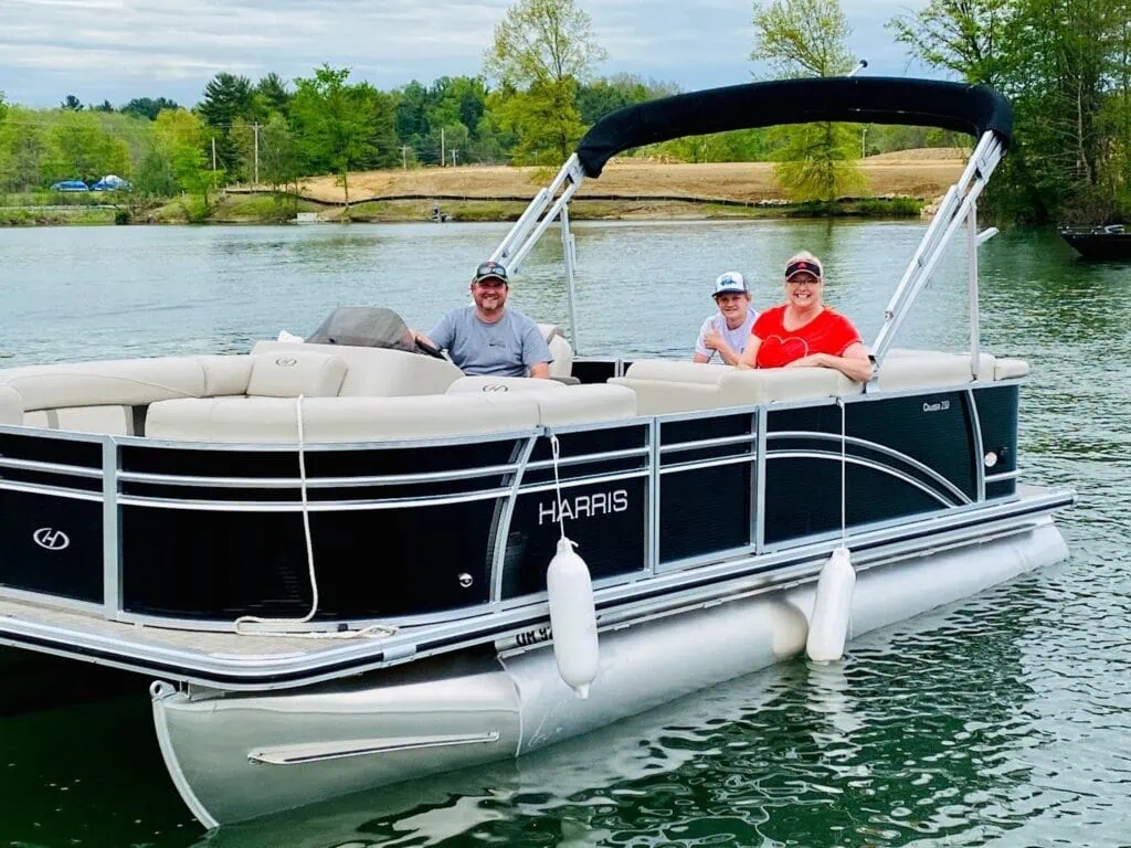 Three people smiling on pontoon boat lake