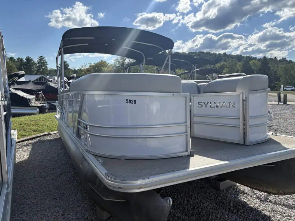 White Sylvan pontoon boat outdoors under blue sky.