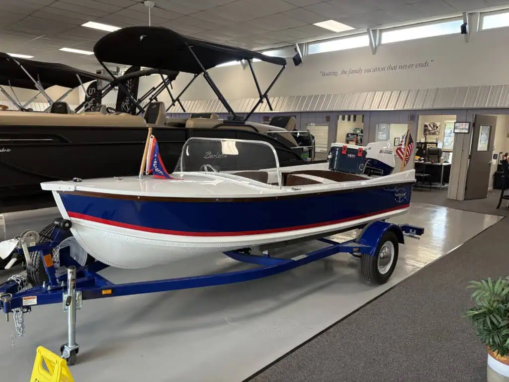 Blue and white boat displayed indoors on trailer.