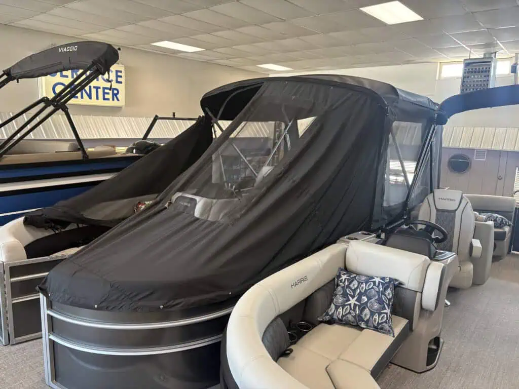 Pontoon boat with black canopy in showroom.