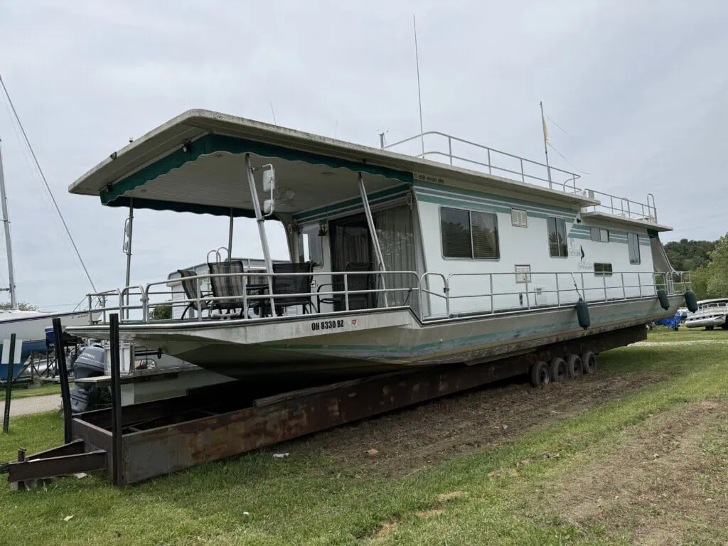 Large houseboat on trailer in grassy lot