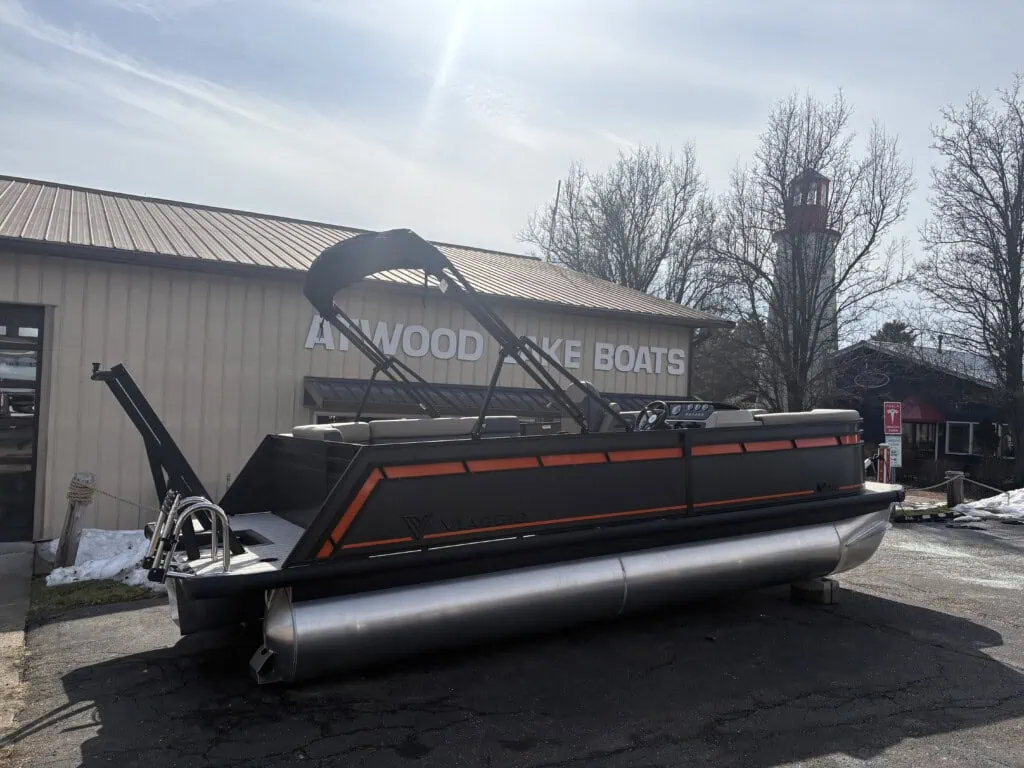 Pontoon boat displayed outside at dealership in winter.